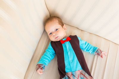 High angle portrait of cute baby lying on sofa at home
