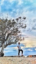 Girl standing on grass against cloudy sky