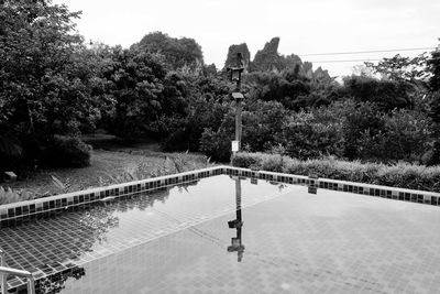 Footpath by swimming pool in park against sky