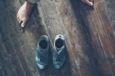 Low section of man standing by shoes on floor