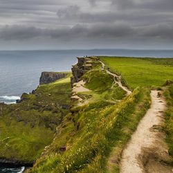 Scenic view of cliff by sea against sky