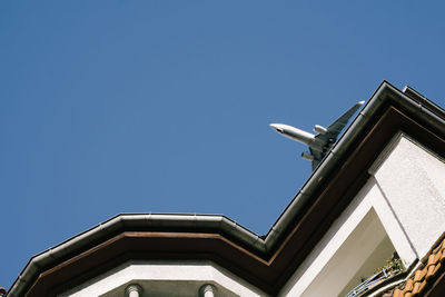 Low angle view of airplane flying over building against clear sky