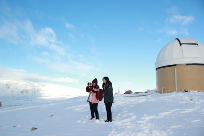 Rear view of people standing on snow covered landscape