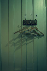 Brown wooden cloth hanger with shadow hanging on metal hook on wooden wall background. 