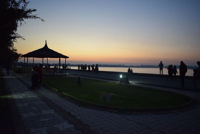 People at beach against sky during sunset