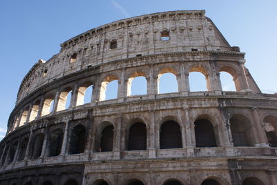 Low angle view of coliseum against blue sky