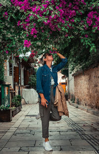 Pretty adult woman smelling spring flowers in street.