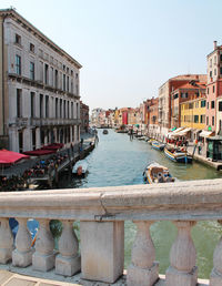 Canal in city against clear sky