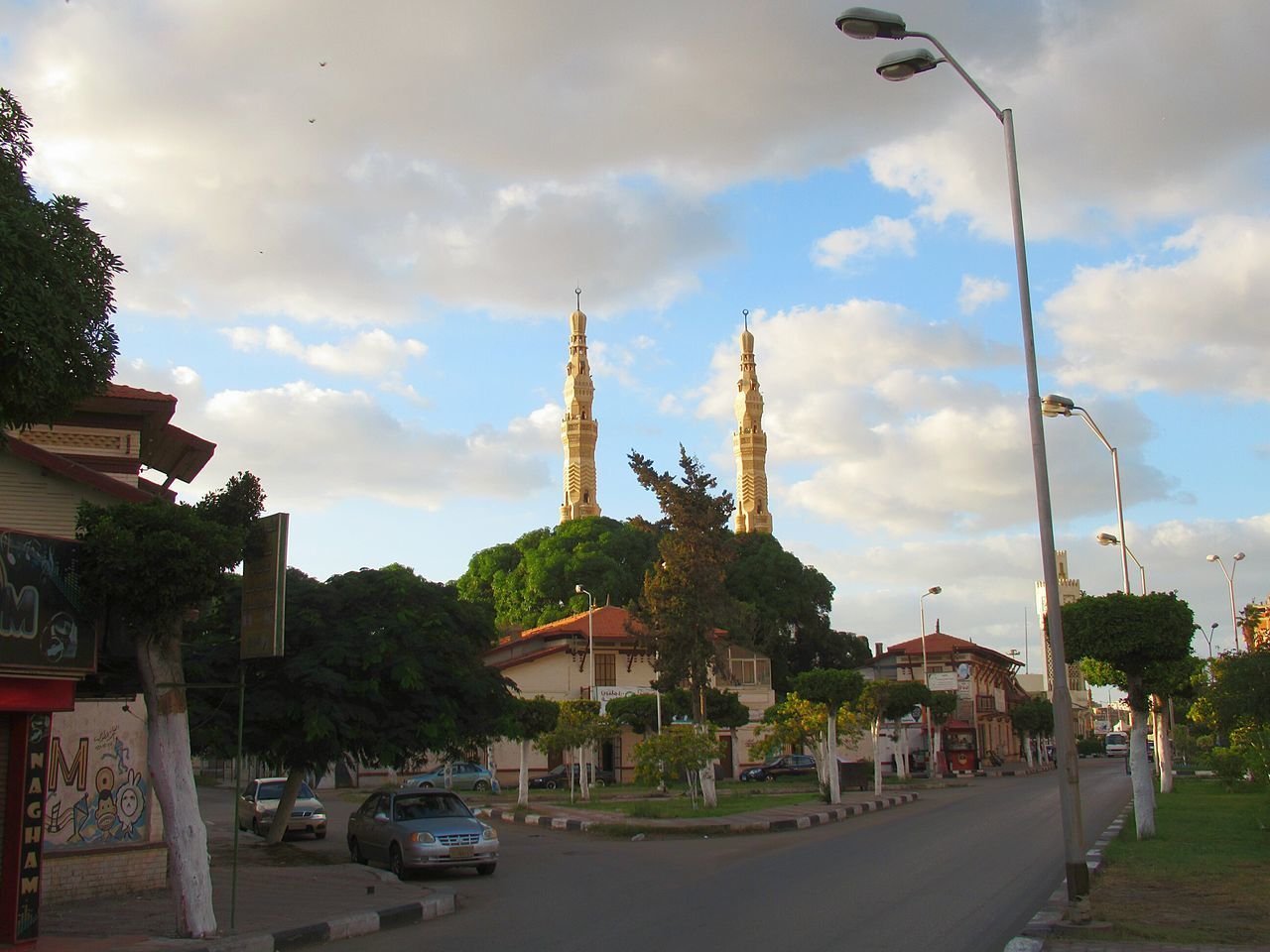 CARS ON ROAD AMIDST BUILDINGS AGAINST SKY