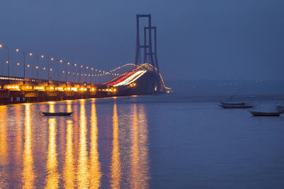 Illuminated boats in sea against clear sky at night