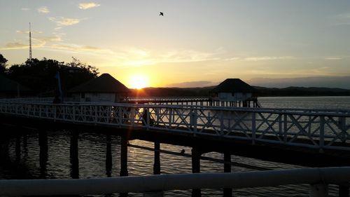 Silhouette of pier on sea during sunset