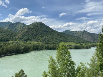 Scenic view of river by mountains against sky