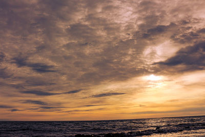 Scenic view of sea against dramatic sky during sunset