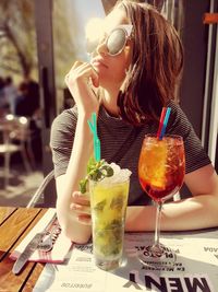 Midsection of woman drinking glass on table at restaurant