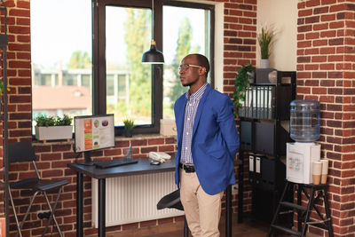 Portrait of young man standing against window