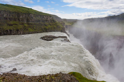 Scenic view of waterfall against sky