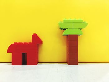 Close-up of plastic toys on floor against yellow wall