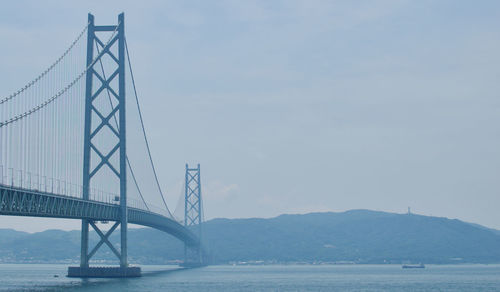 Suspension bridge over sea against sky