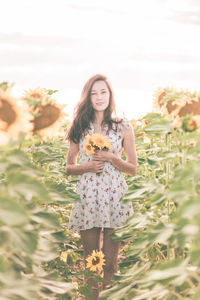 Portrait of a smiling young woman standing against plants