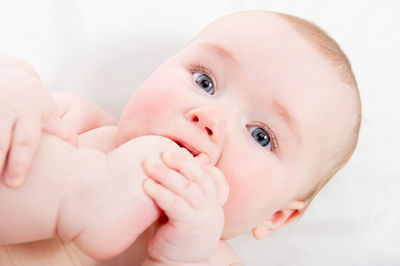 Close-up portrait of cute baby girl lying on bed