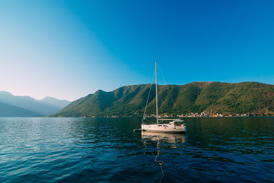 Sailboat in sea against clear blue sky