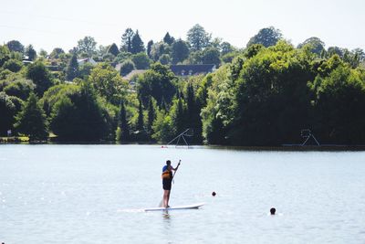 Rear view of man paddleboarding at lake