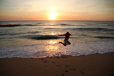 Silhouette man on beach against sky during sunset