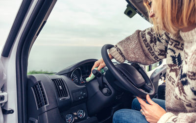 Young woman cleaning dust of the car dashboard