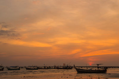 Silhouette boats moored on beach against sky during sunset
