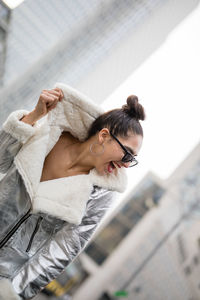 Smiling woman in sunglasses against buildings