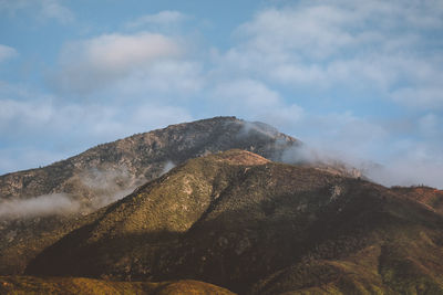 Low angle view of mountain against cloudy sky