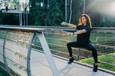 Full length of woman exercising on footbridge at park