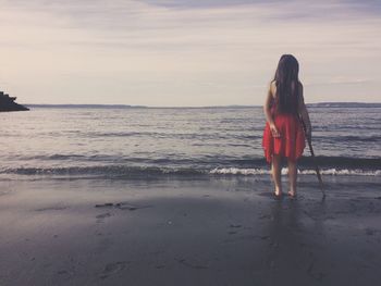 Rear view of girl standing on shore at beach
