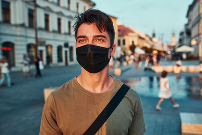 Close-up of man wearing mask looking away while standing on street in city