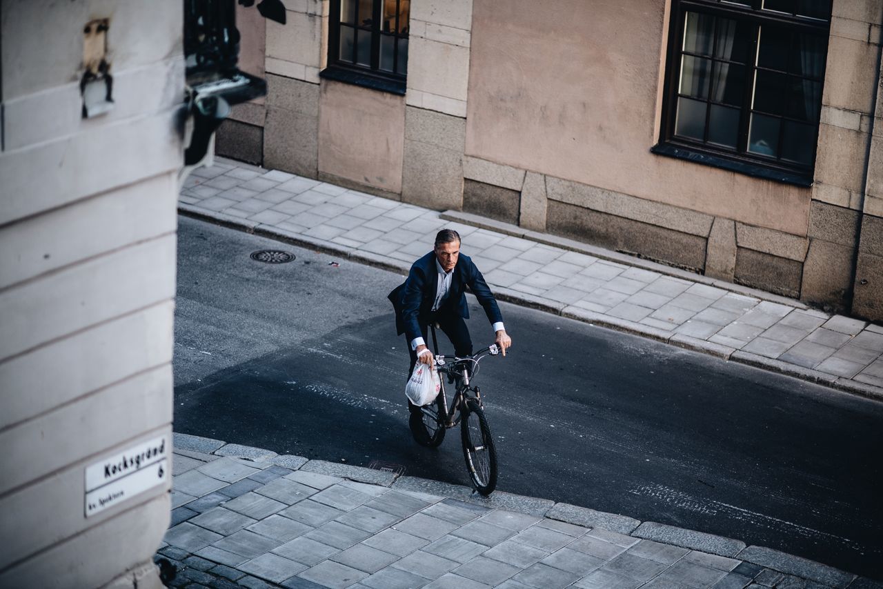 MAN RIDING BICYCLE ON STREET AMIDST BUILDINGS