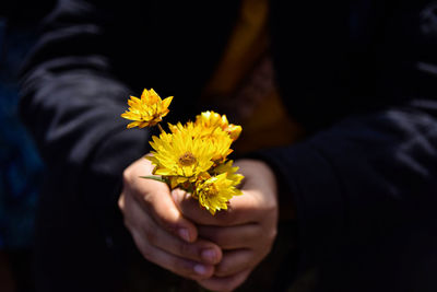 Midsection of woman holding yellow flower