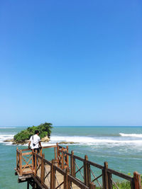 Rear view of people looking at sea against clear sky