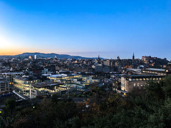 High angle view of illuminated buildings against clear blue sky