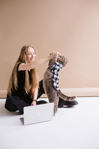 Portrait of young woman sitting on white background