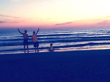 People at beach against sky during sunset