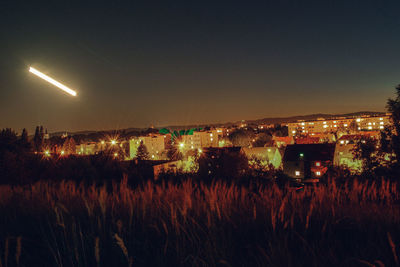 Illuminated field against sky at night