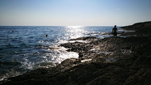 Silhouette man standing on beach against clear sky