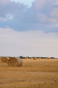 Hay bales on field against sky