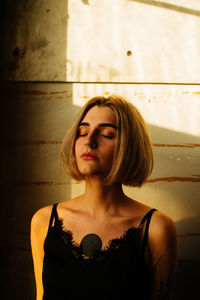 Portrait of a young woman looking away against wall