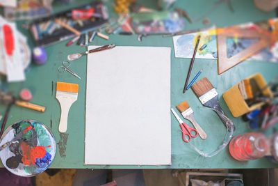 High angle view of blank paper with art and craft equipment on table