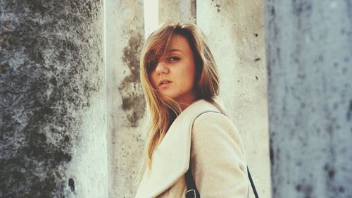 Portrait of beautiful young woman leaning against wall