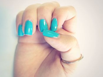 Cropped image of hand holding ring over white background