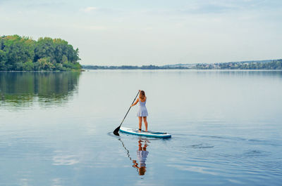 Woman on boat in lake against sky