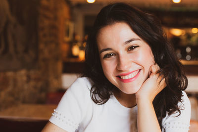 Close-up portrait of smiling young woman sitting in restaurant