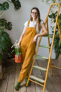 Portrait of smiling young woman standing against plants